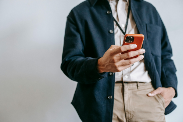 A casually dressed professional holds a smartphone and looks at the screen.